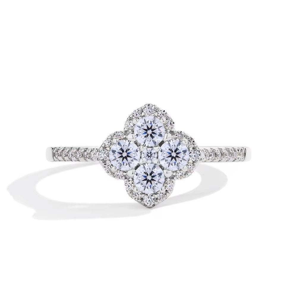 An elegant Clover Leaf inspired cocktail ring with a round-cut moissanite gemstone, surrounded by a floral halo of sparkling stones on a rhodium-plated sterling silver band.
