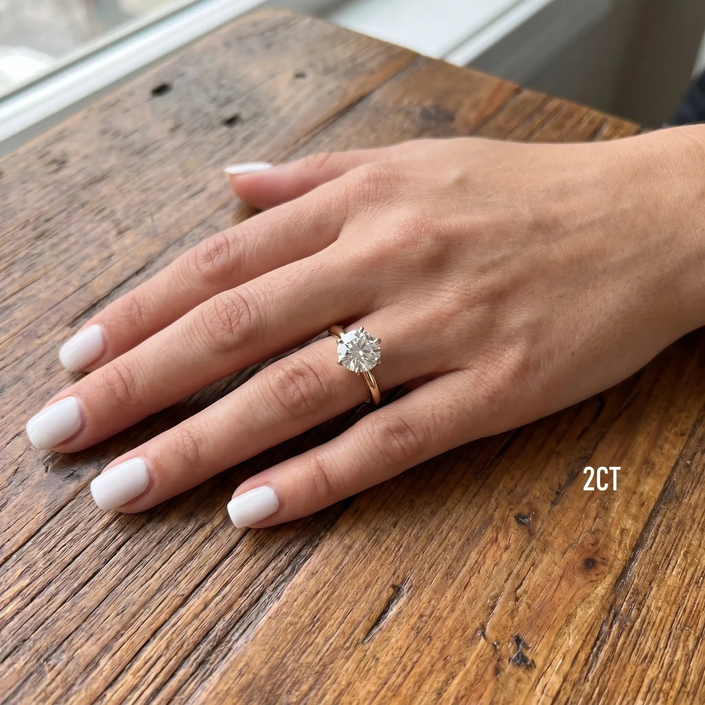 Shenae tulip solitaire ring worn on a hand resting on a wooden table