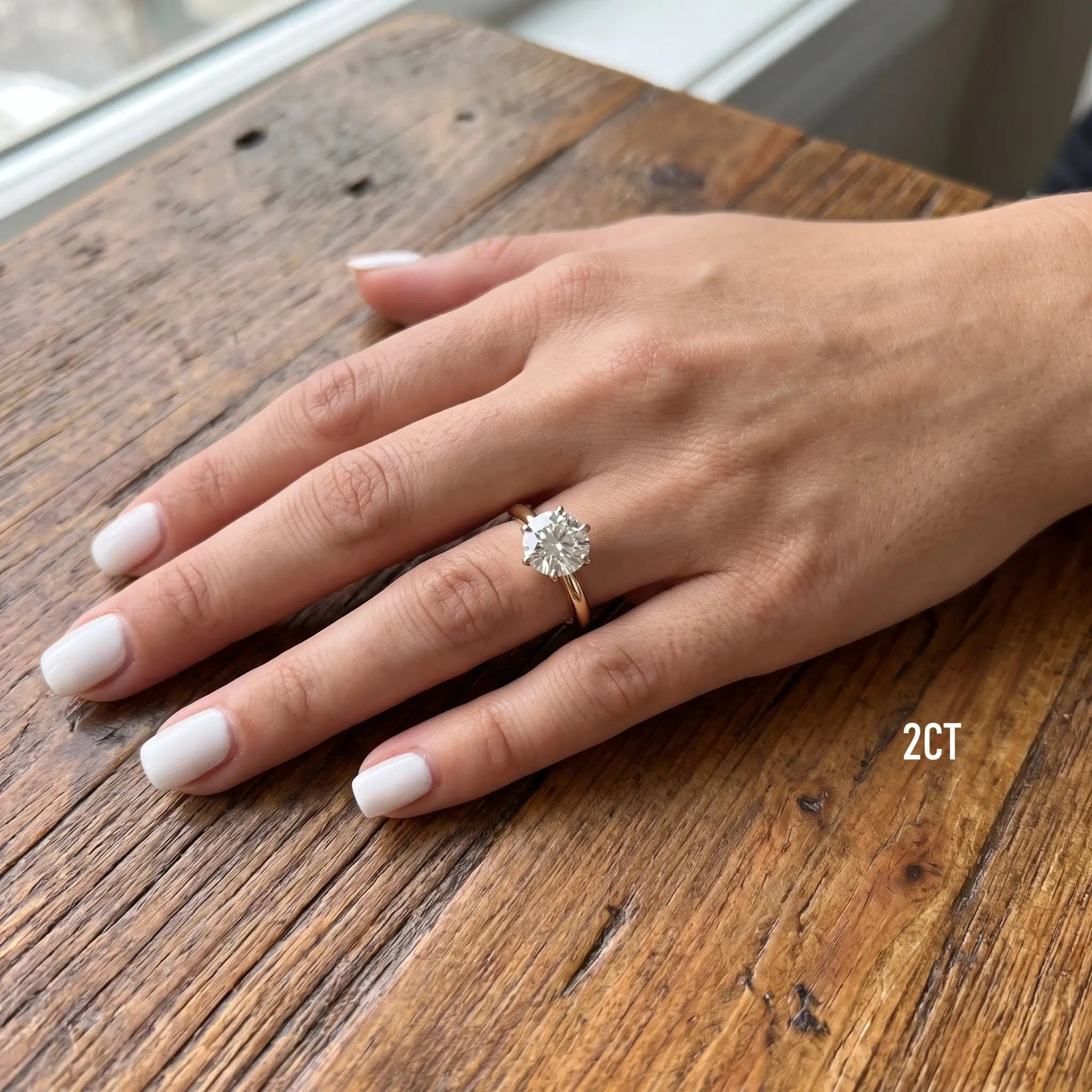 Shenae tulip solitaire ring worn on a hand resting on a wooden table