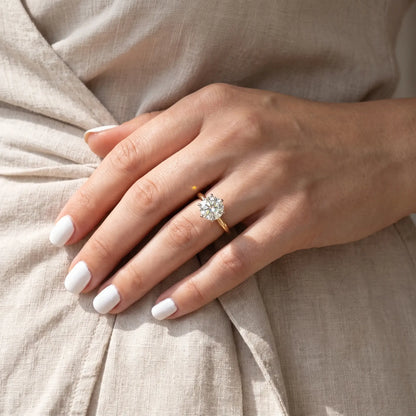 Hand with white nails wearing the Shenae tulip solitaire ring against a dress